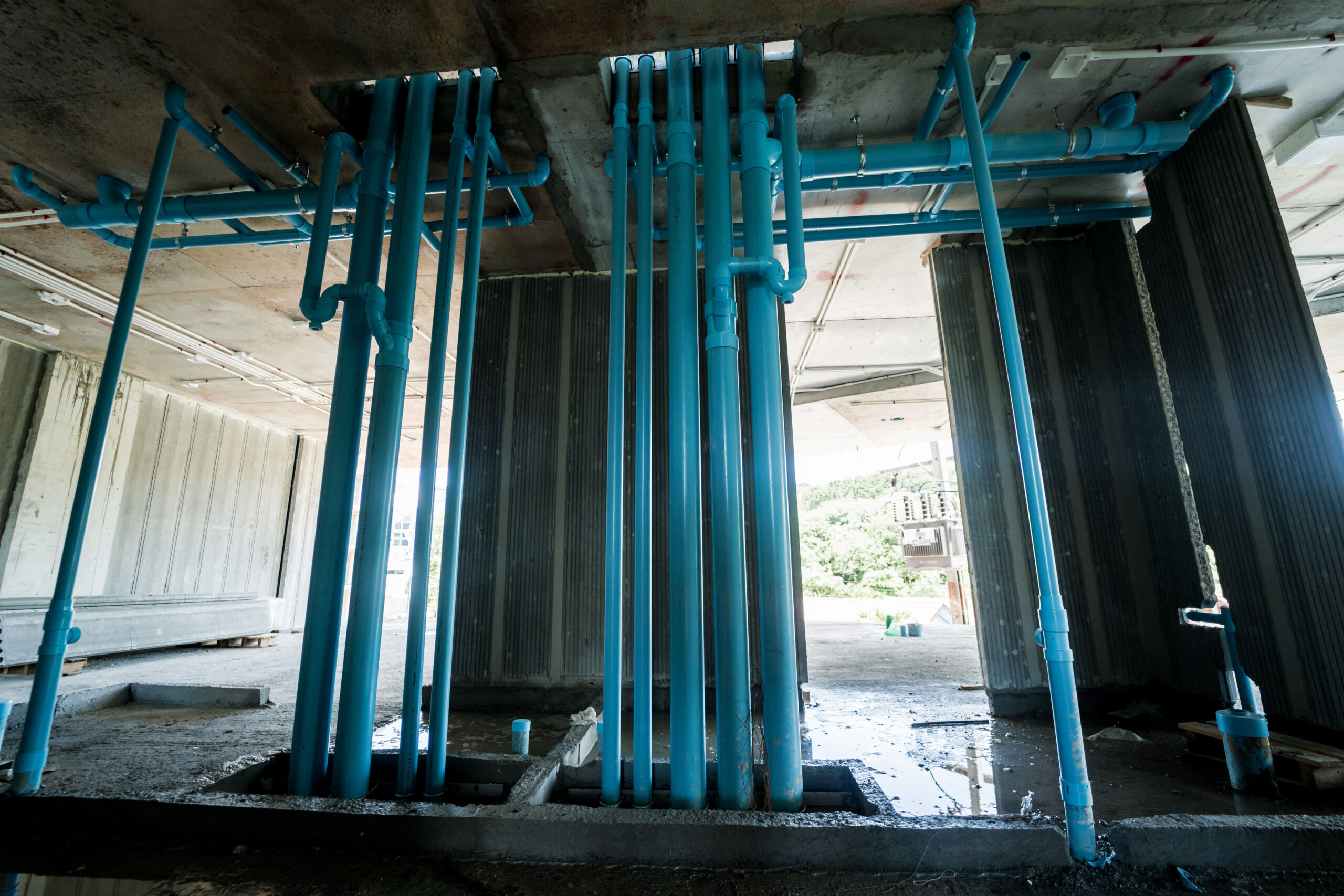 A large building currently under construction that has many blue pipes commercial plumbing project