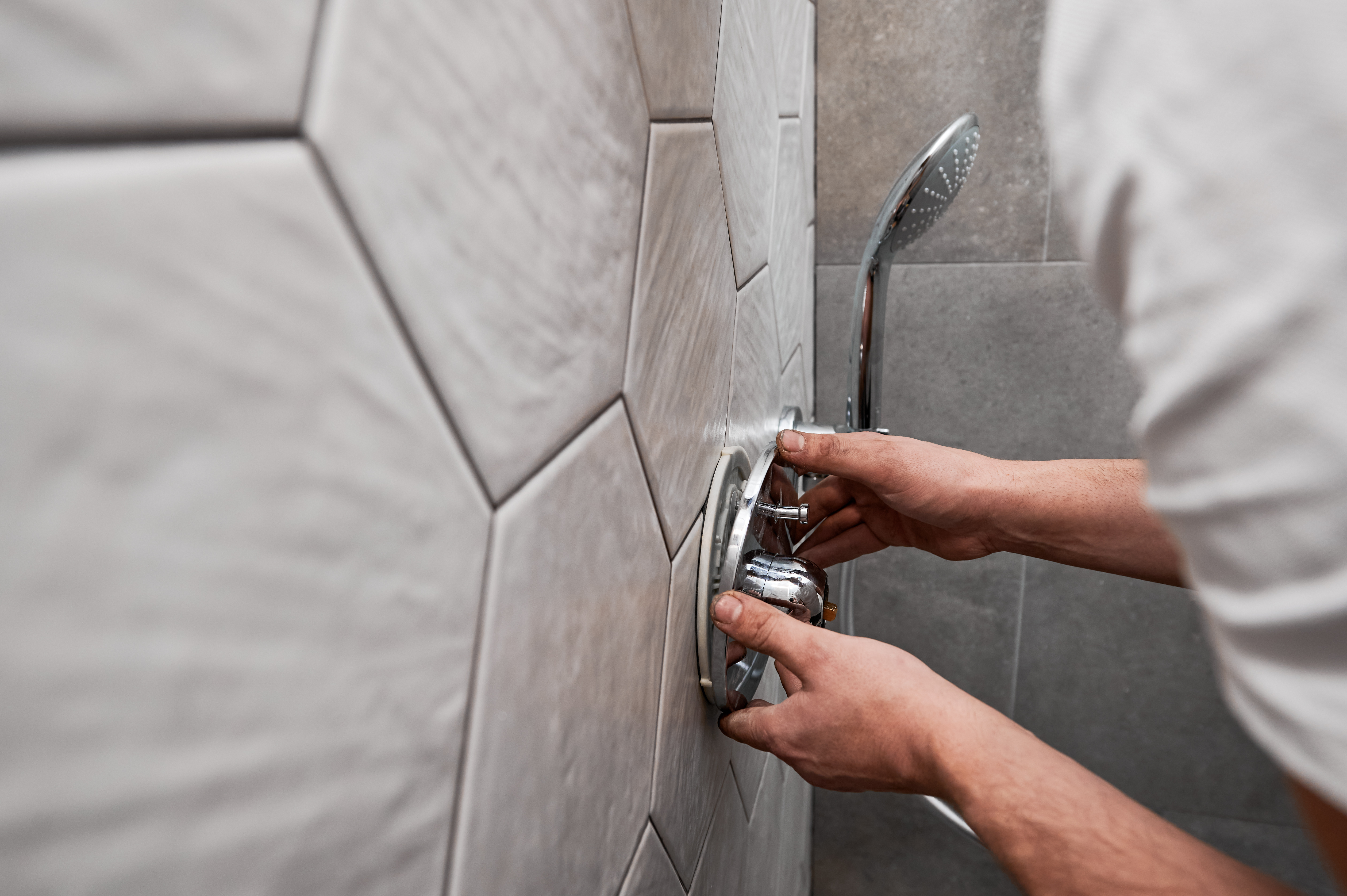 Male plumber hands installing shower faucet handle in bathroom. plumbing fixture installation