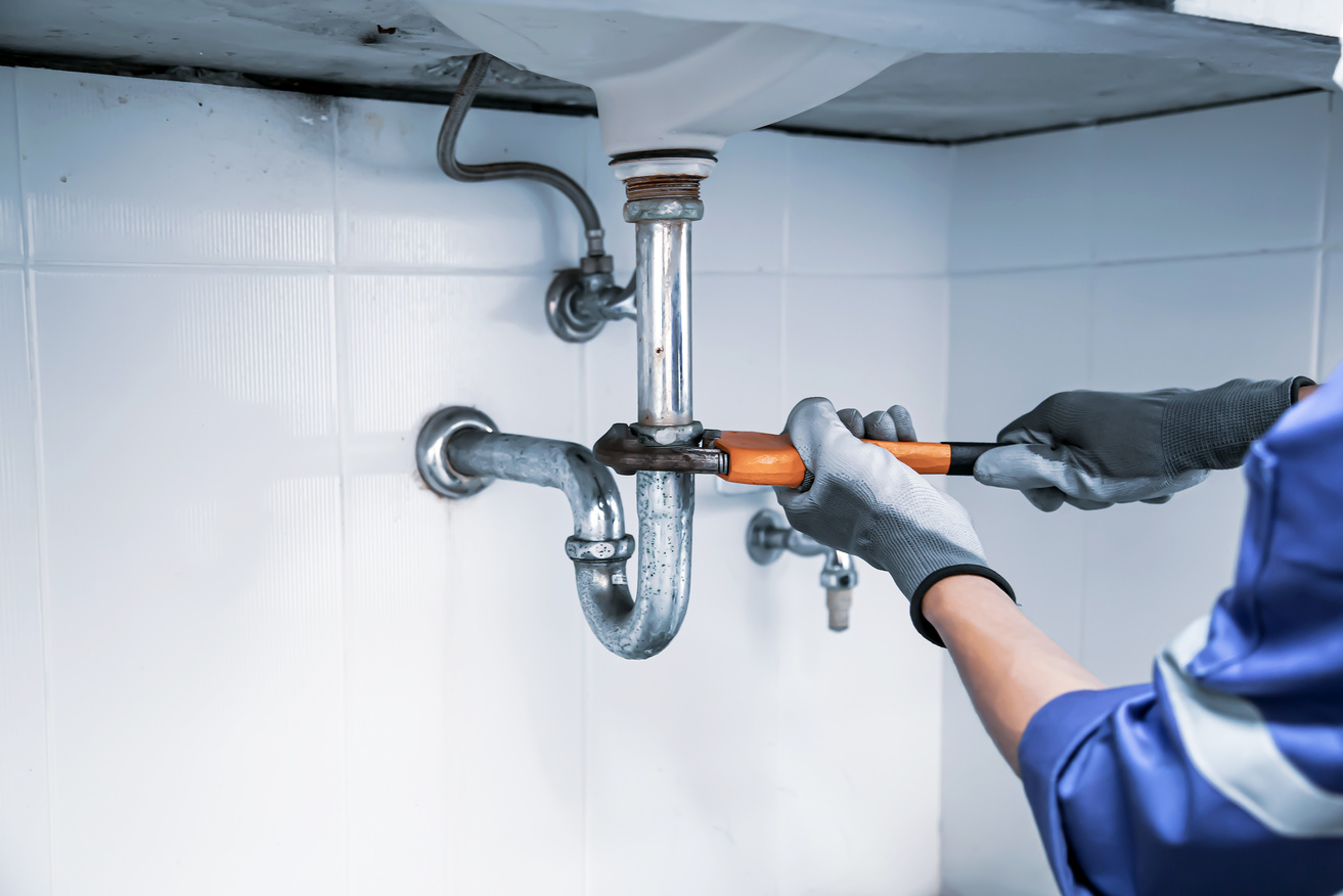 plumber tightening pipes under the sink